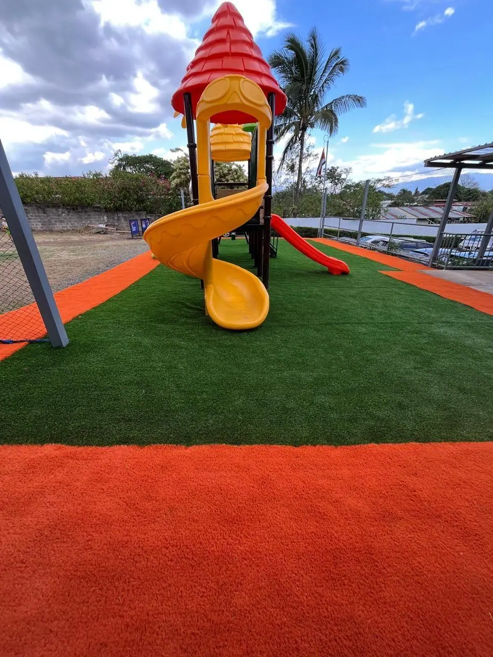 Área de juegos infantil con césped artificial verde y naranja instalada por Jardines BR